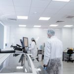 Profissionais realizam pesquisas em um laboratório farmacêutico moderno, equipado com instrumentos científicos.