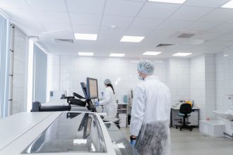 Profissionais realizam pesquisas em um laboratório farmacêutico moderno, equipado com instrumentos científicos.