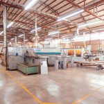 Interior amplo e organizado de uma fábrica industrial moderna, com máquinas e estruturas de produção.