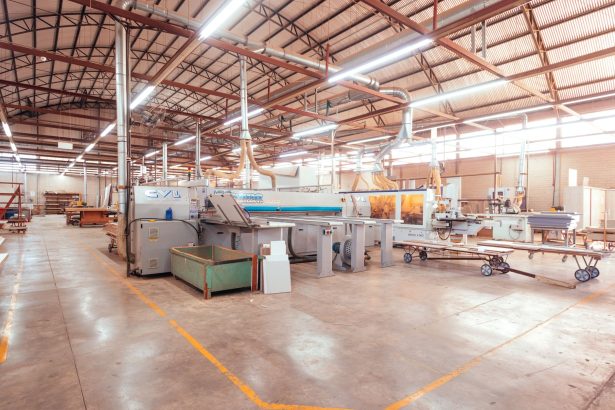 Interior amplo e organizado de uma fábrica industrial moderna, com máquinas e estruturas de produção.