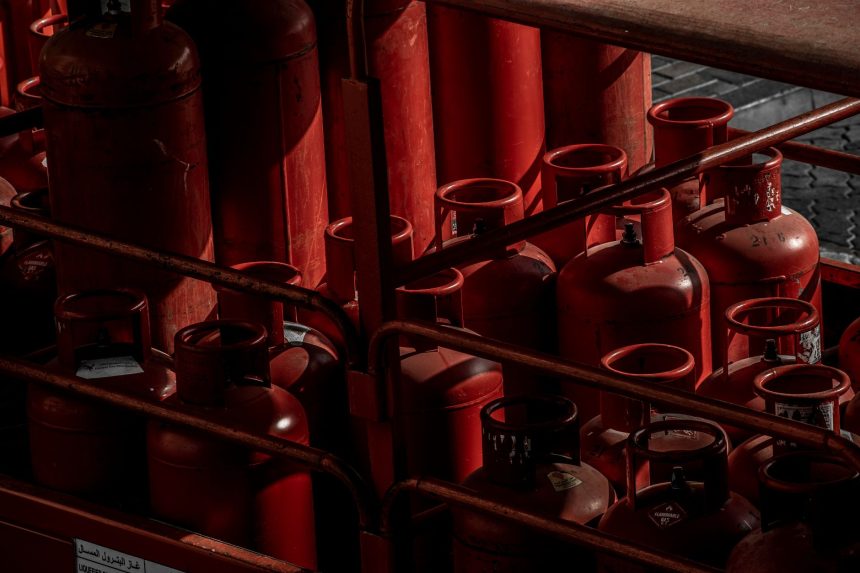 Cilindros de gás vermelhos armazenados em uma área industrial.