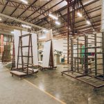 Interior de uma fábrica industrial ampla e iluminada, com máquinas e estruturas de armazenamento.