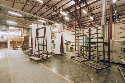 Interior de uma fábrica industrial ampla e iluminada, com máquinas e estruturas de armazenamento.