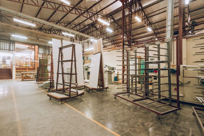 Interior de uma fábrica industrial ampla e iluminada, com máquinas e estruturas de armazenamento.