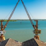 Dois guindastes sobre a margem de um rio no Rio Grande do Sul