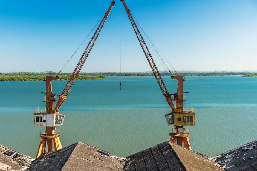 Dois guindastes sobre a margem de um rio no Rio Grande do Sul