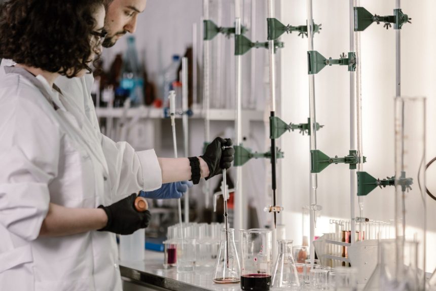 Pesquisadores de jaleco trabalham com tubos de ensaio em um laboratório moderno.